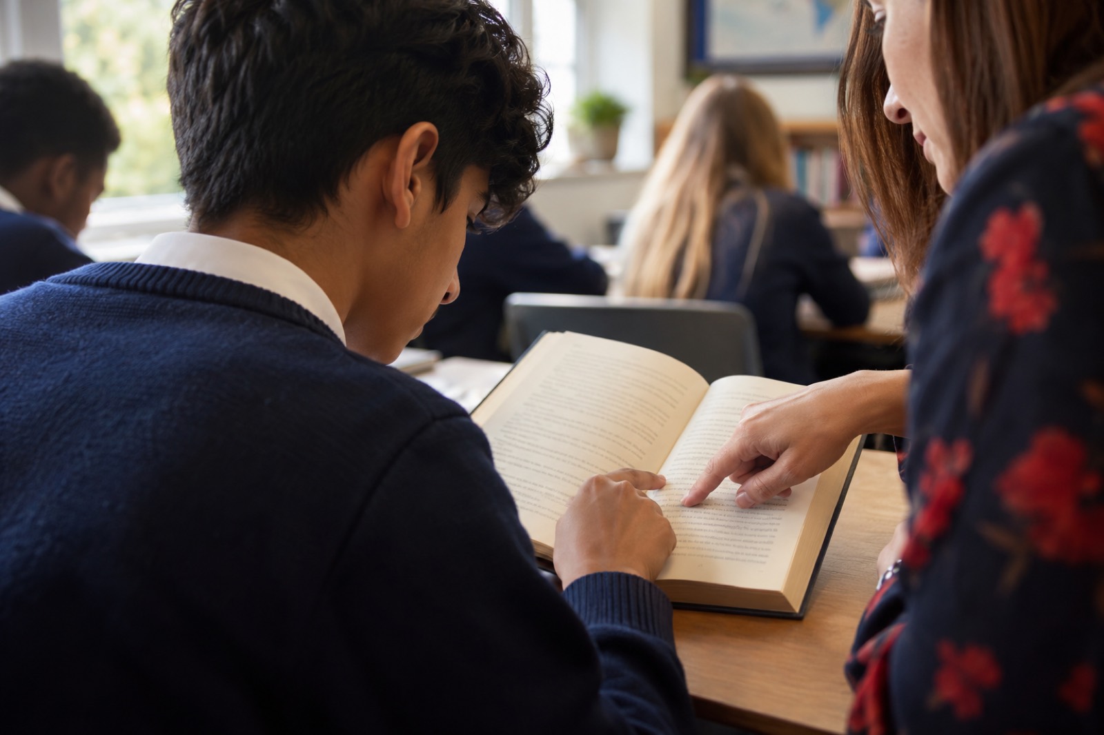 A pupil reading with a teacher's support